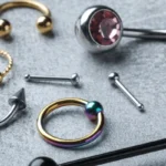 A collection of assorted body piercing jewelry including rings, studs, and barbells in various colors and styles.